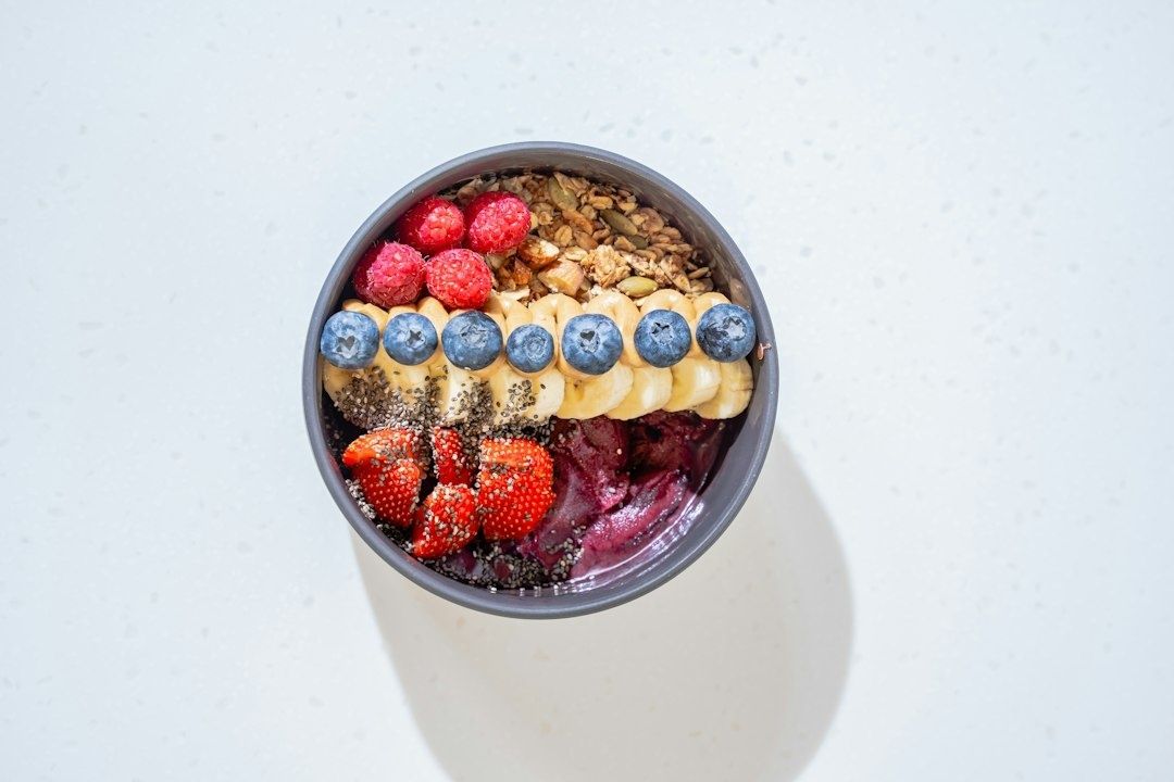 Färgstark skål med bär, banan, granola och krämig lila bas